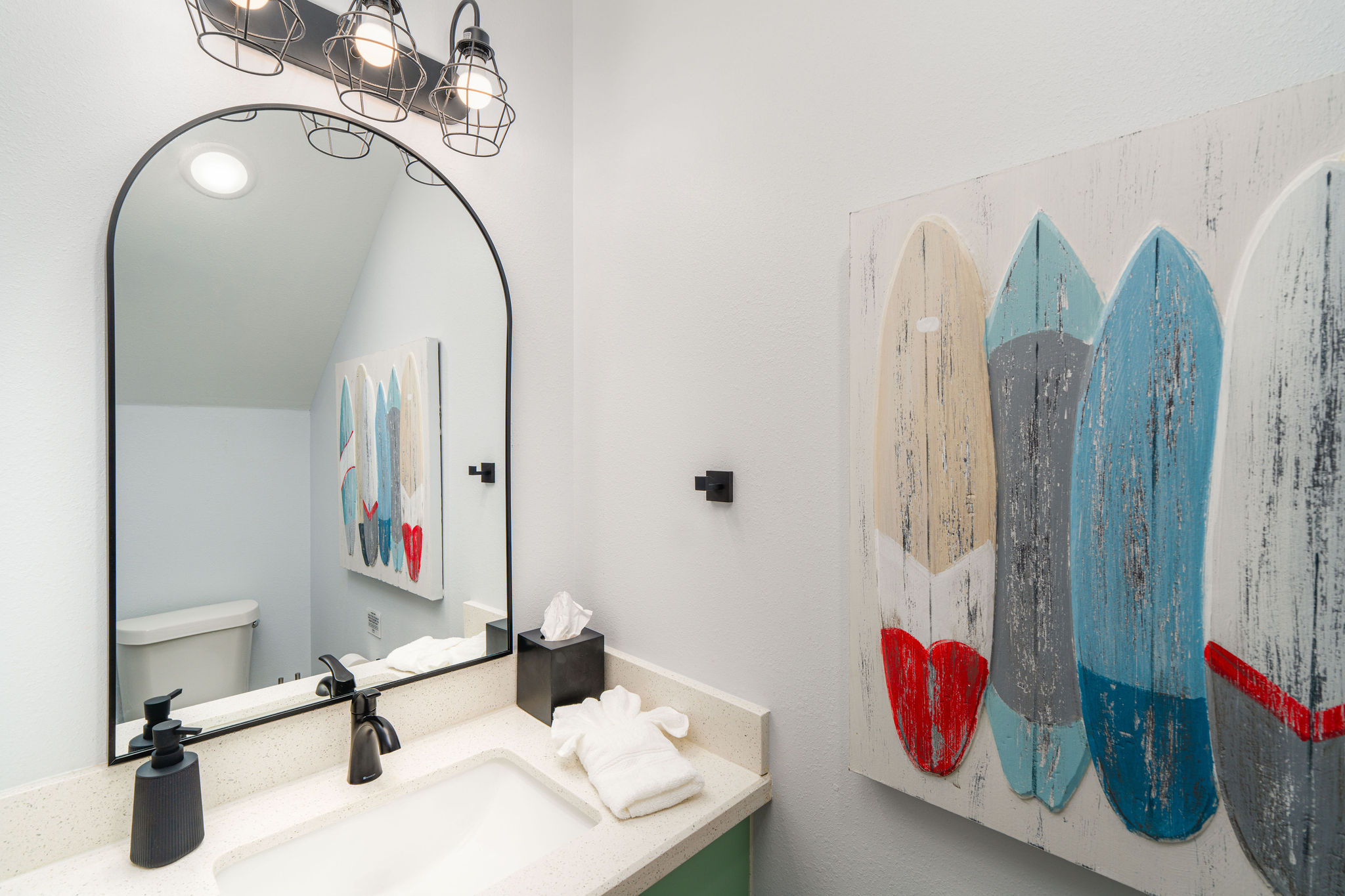 Half bath — surfboard art, powder room downstairs so the bedrooms stay private.