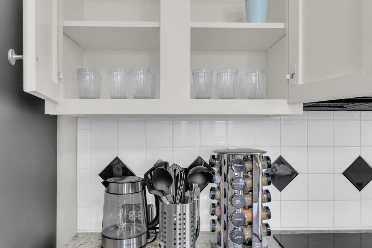 Well-equipped kitchen with practical essentials like glassware, spices, utensils, and a kettle to make cooking comfortable and convenient.