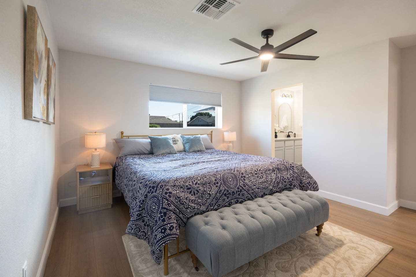 Cozy, modern bedroom with plush bedding, ceiling fan, and ensuite bathroom access