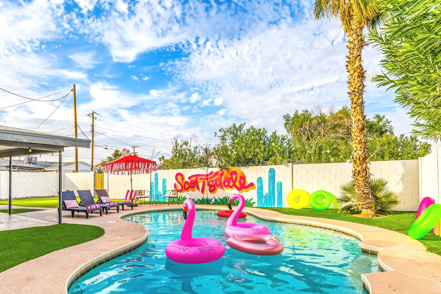 Lounge in style by the pool with vibrant flamingo floats and playful desert-themed art that screams vacation mode.

