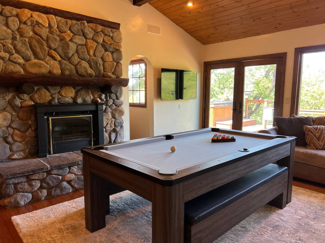 A second living room with a pool table, additional ping table topper, speaker system, and 55" 4K TV.