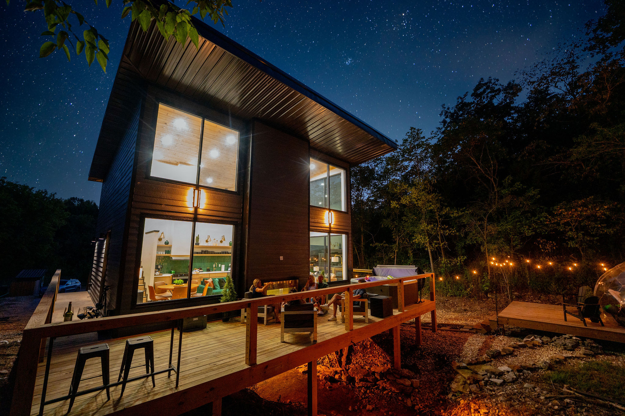When the sun goes down, the glass cabin glows against the quiet Ozark woods.