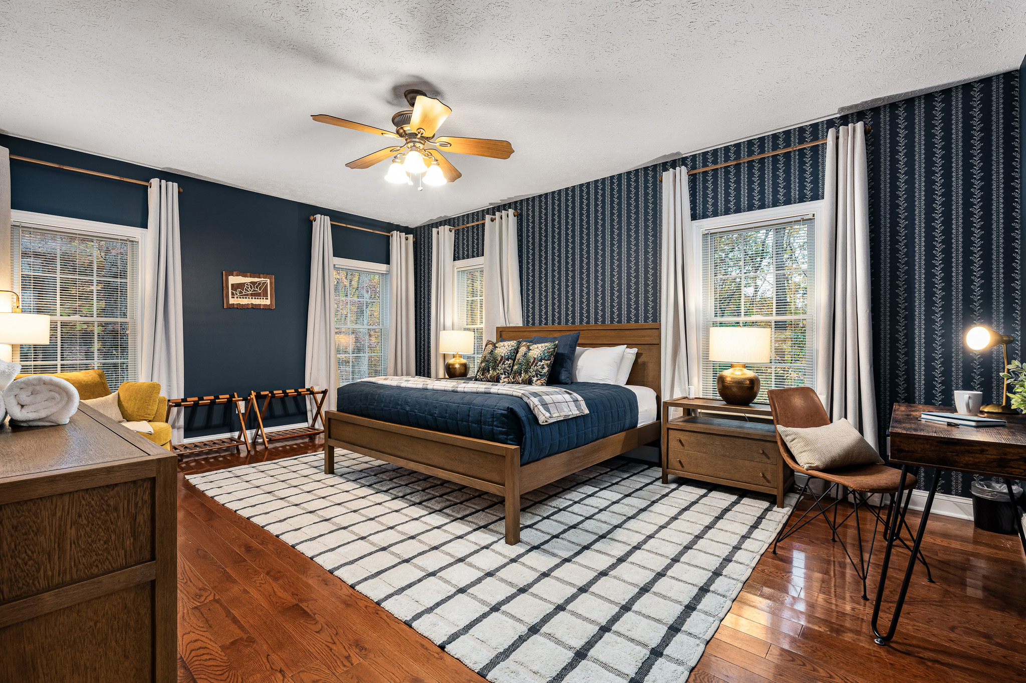 Spacious king suite with rich blue accents, stylish wallpaper, and warm wood furniture — your retreat after a day of adventure.