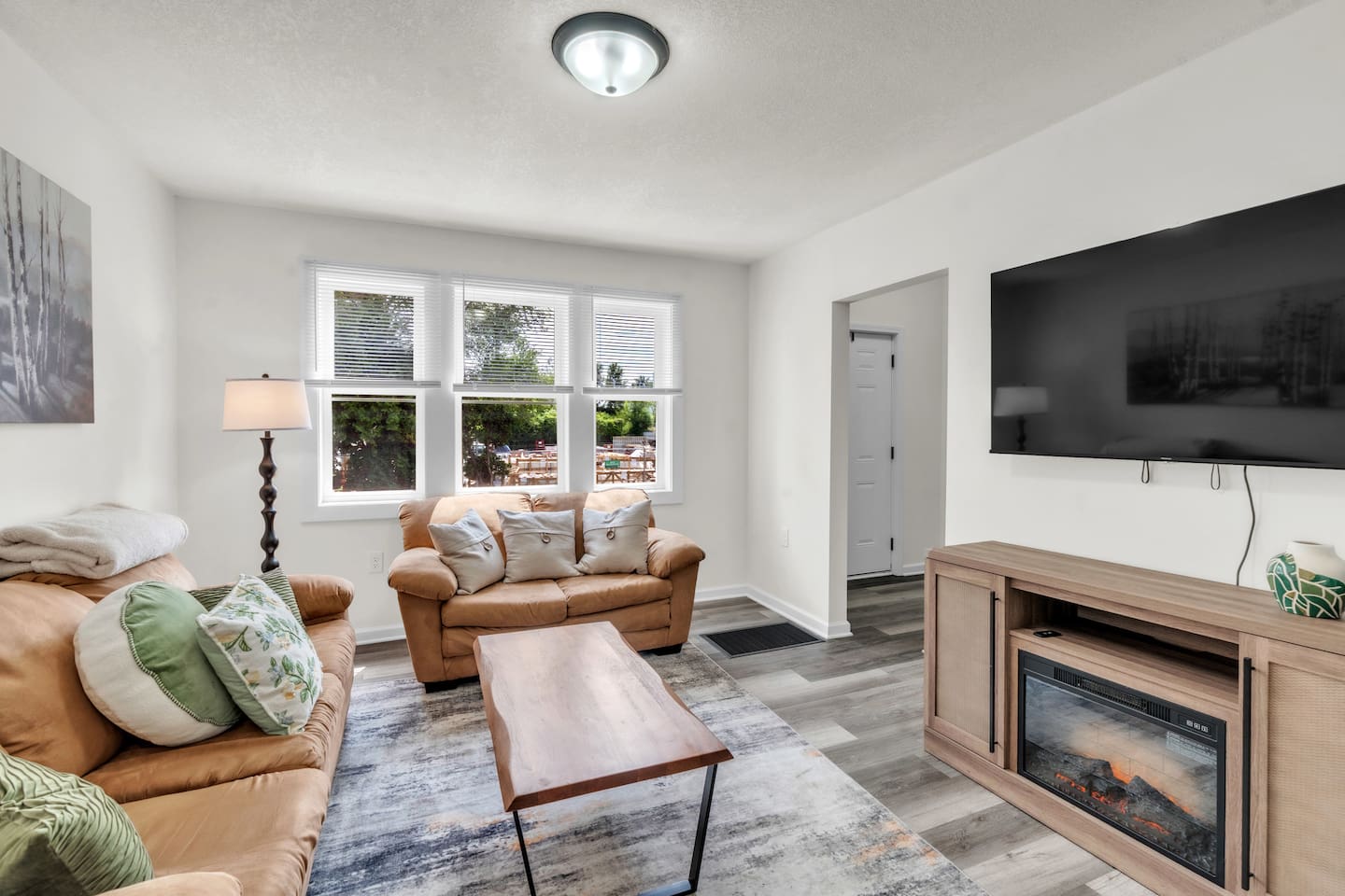 The living room offers comfort with cozy couches, a large window that brings in natural light, and a TV, perfect for a laid-back evening.
