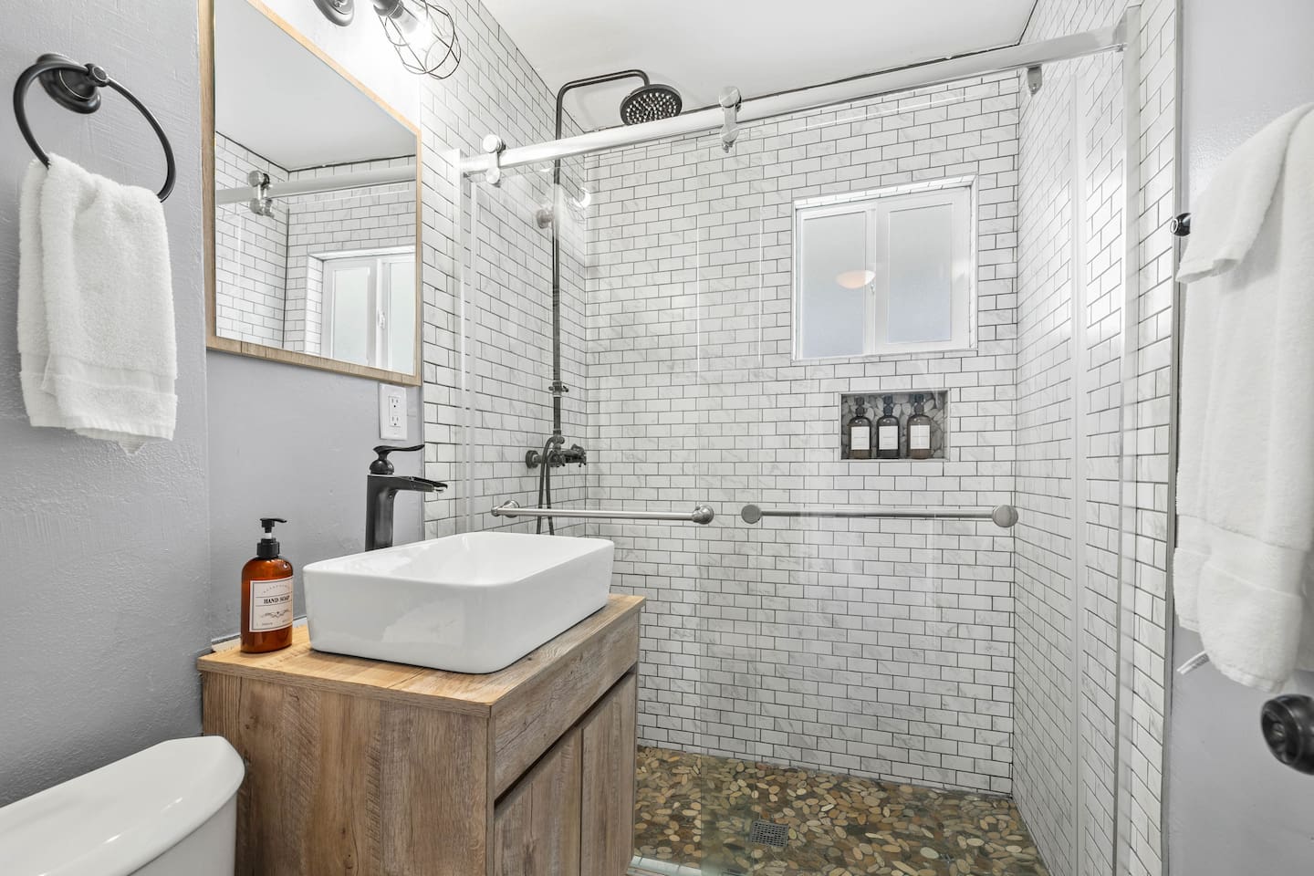 Sophisticated full bathroom featuring an elegant sink with a stylish faucet, a sleek mirror, and a glass door shower. Perfect lighting enhances the ambiance, creating a bright and relaxing space ideal for refreshing moments.