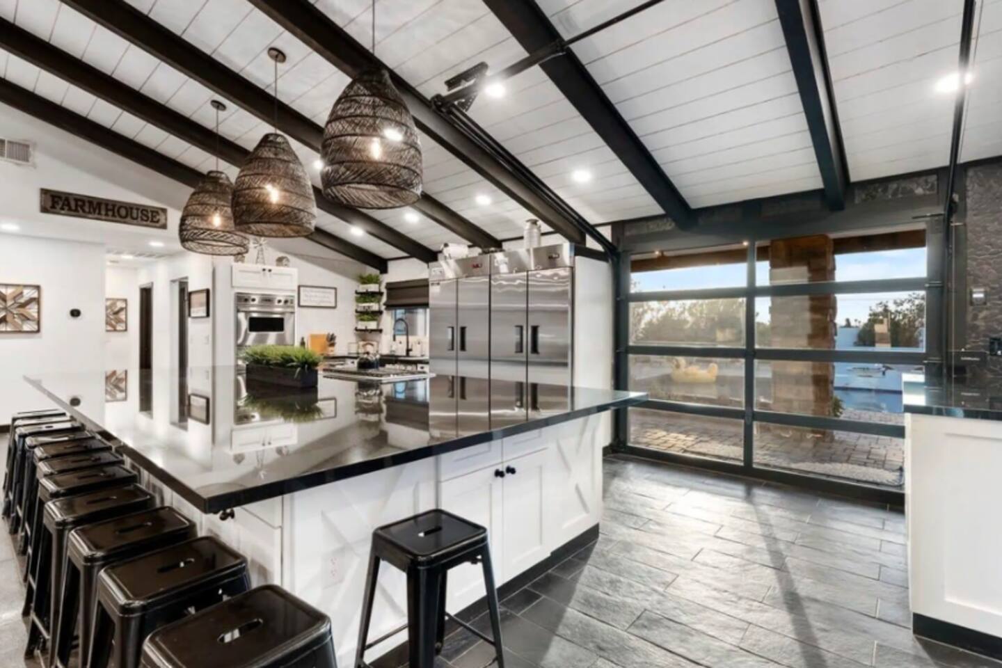 A glass garage door slides open to the pool right from the farmhouse kitchen — true indoor-outdoor living.
