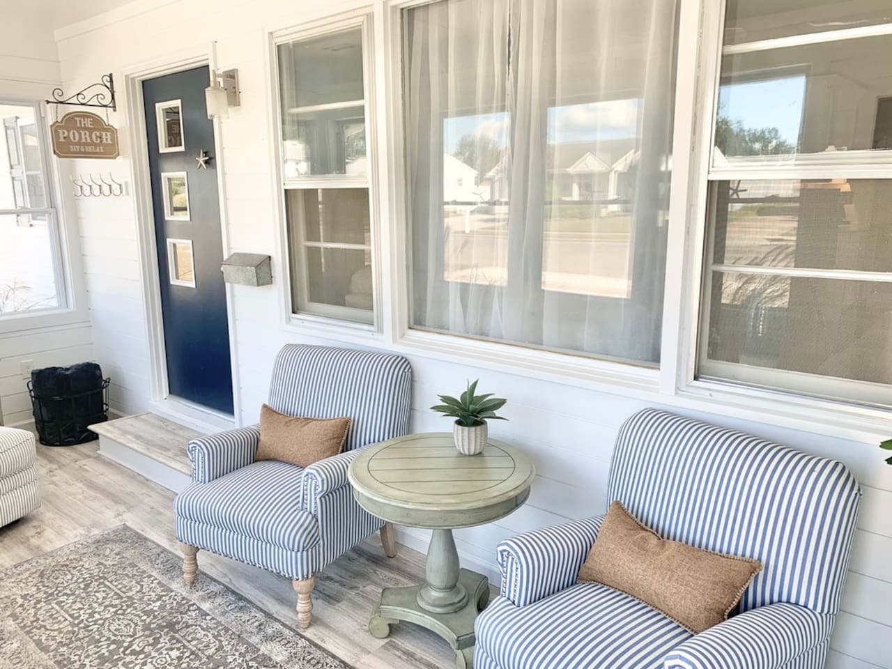 Enjoy a quiet moment in our bright sunroom, featuring comfortable blue-and-white striped armchairs and a classic pedestal side table. This cozy nook is perfect for morning coffee or getting lost in a good book.