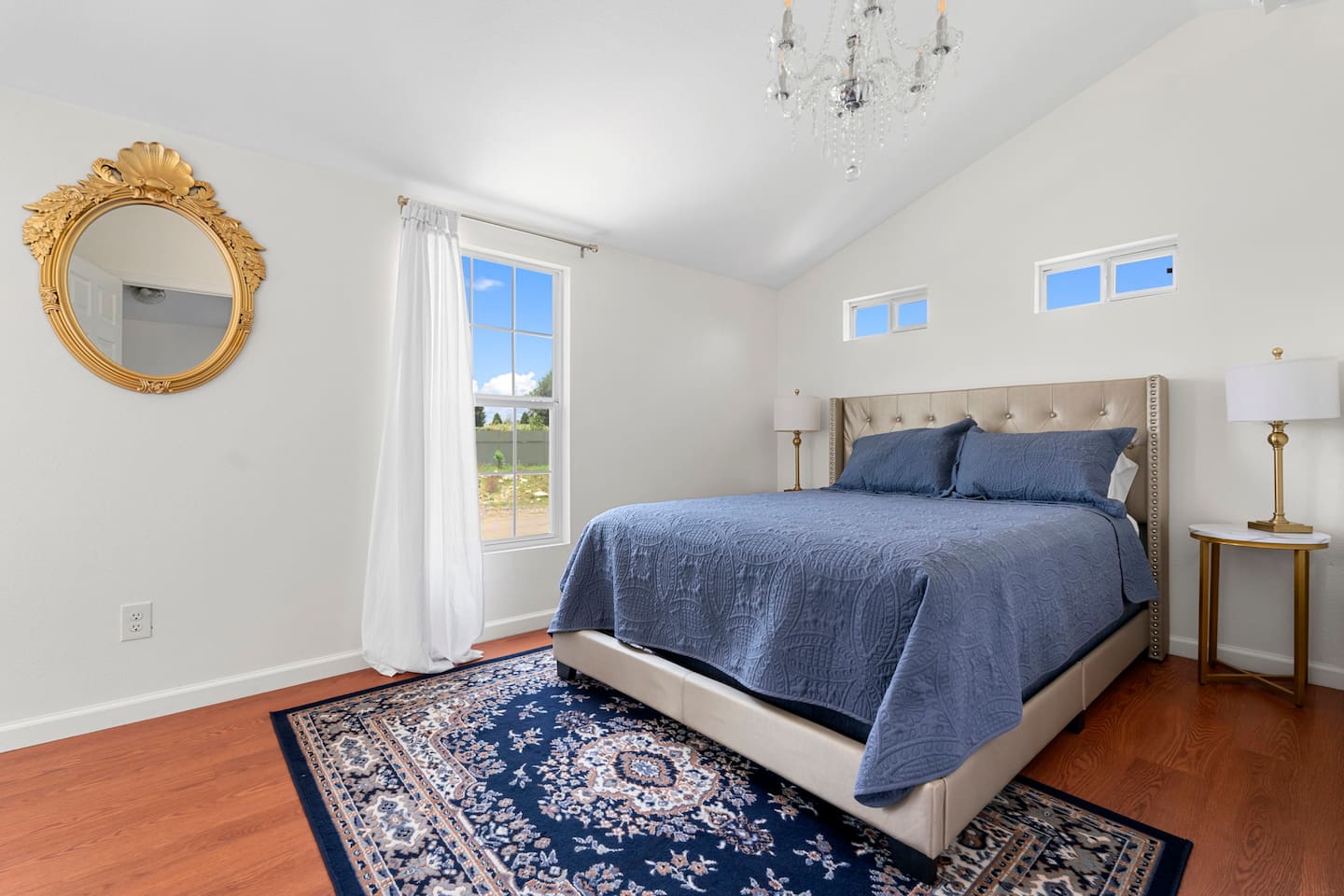 Vaulted ceilings and clerestory windows fill this bedroom with light, while a plush bed and patterned rug create a peaceful spot to unwind.