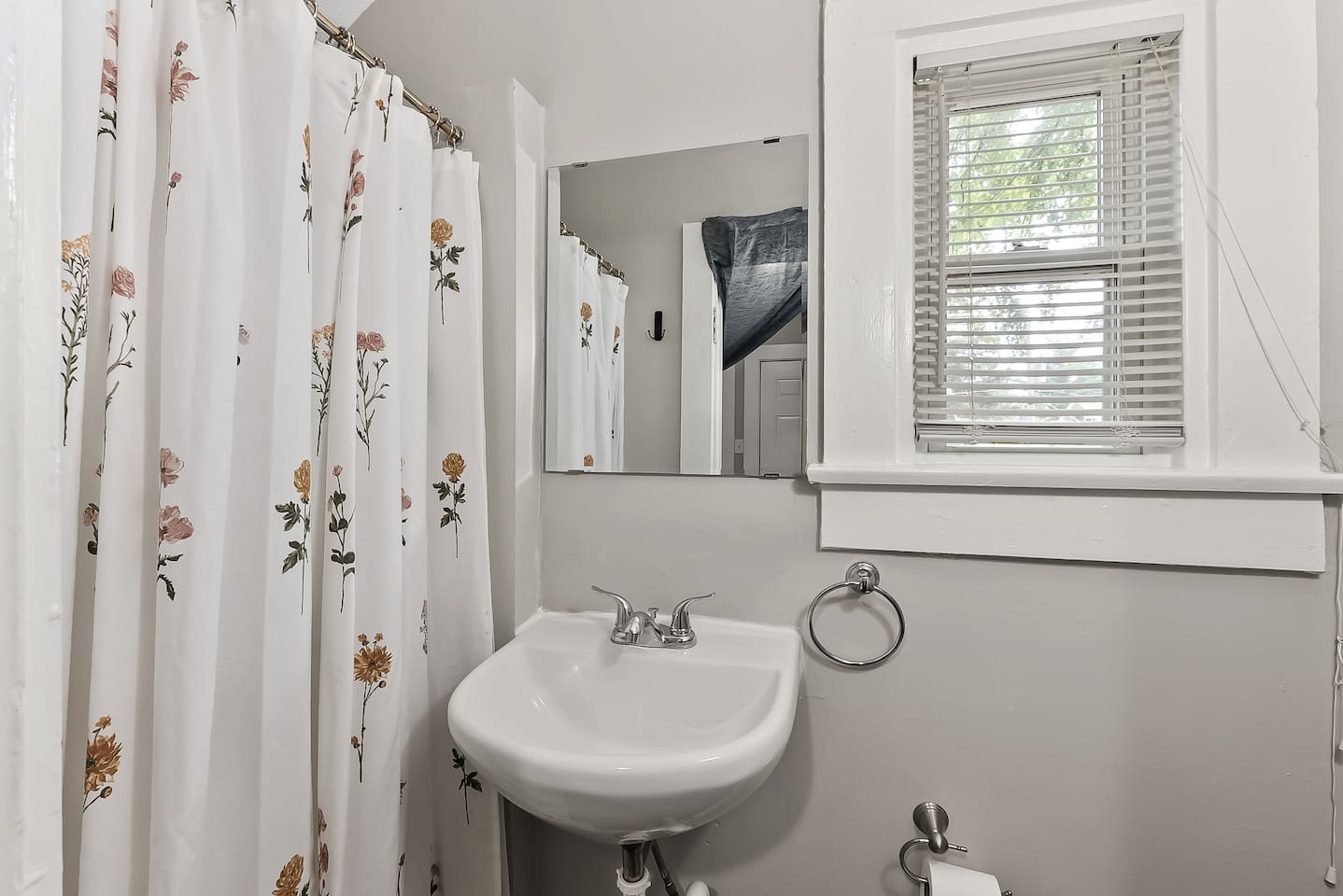 A clean, well-lit full bathroom with a shower/tub combo and pedestal sink — simple and functional.
