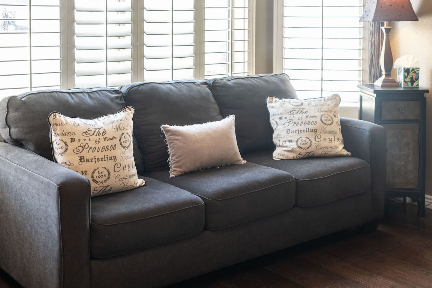 Sink into the plush sofa in the front sitting area, framed by light-filtering plantation shutters — a peaceful spot to start or end your day.