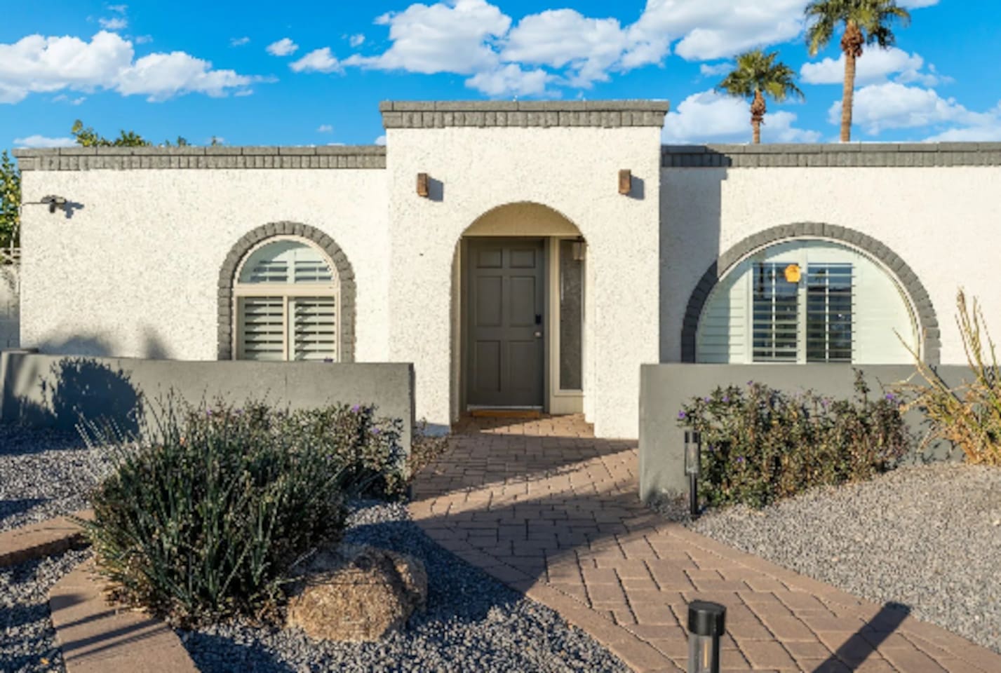 A striking arched entry framed by desert landscaping sets the tone before guests even step inside, low-maintenance and effortlessly stylish.