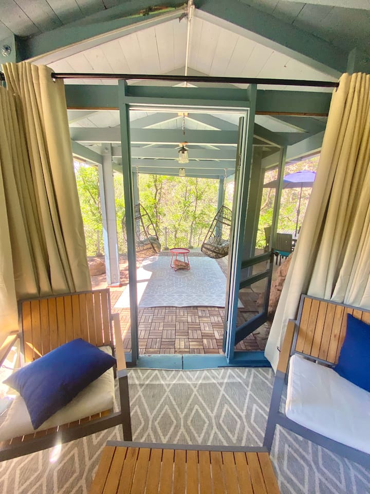 Screen in portion of the gazebo looking to the hanging egg chairs and cliffside.