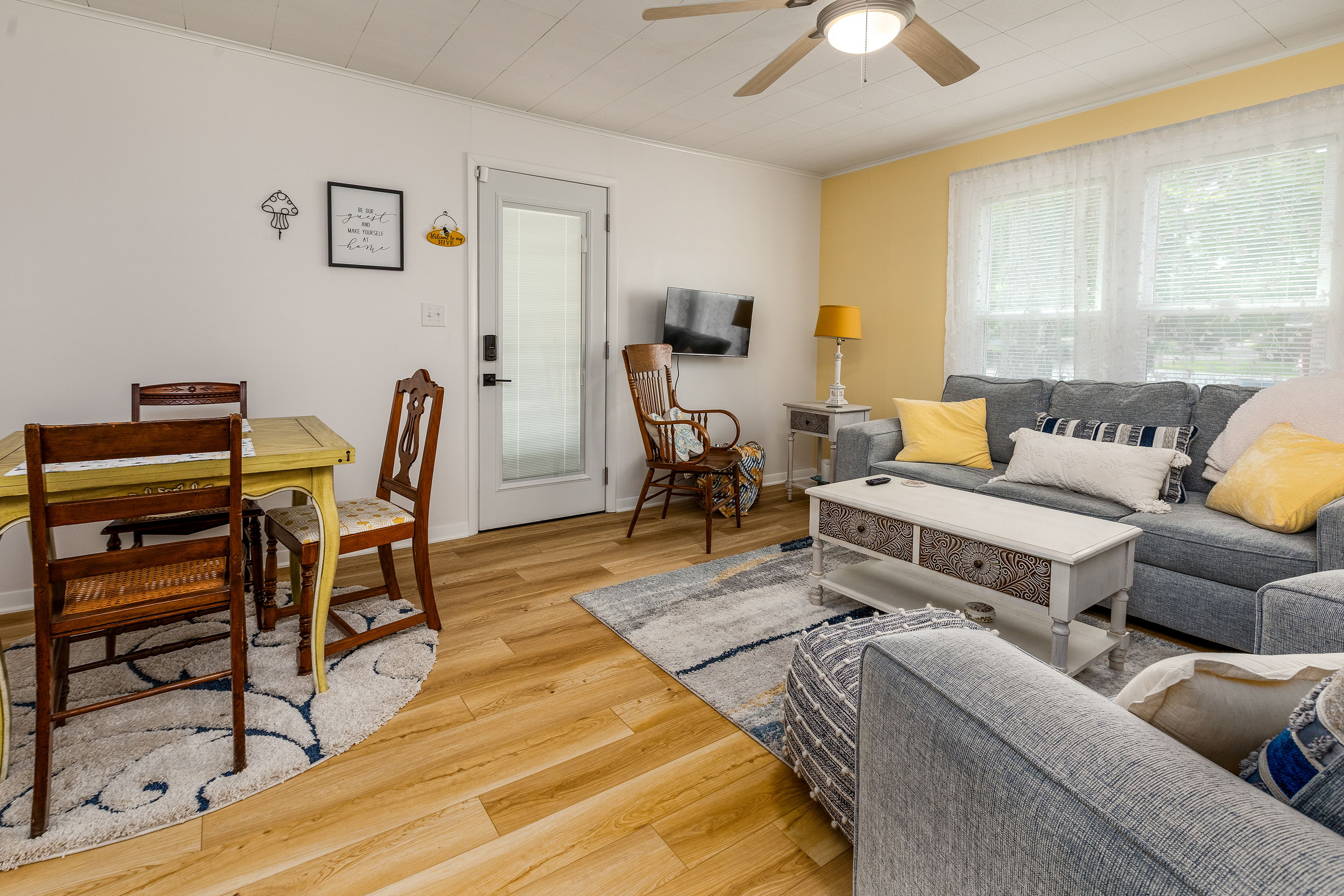 Sweet as honey and just as relaxing—our living room features a comfy sofa and chair set, two rocking chairs, and an expandable dining table perfect for meals or games. Bee-themed decor adds a playful, sunny vibe throughout the space!