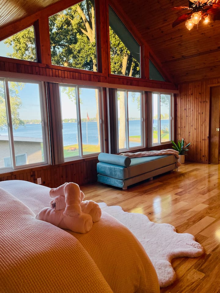 Bedroom with floor-to-ceiling windows offering peasceful views of the lake.