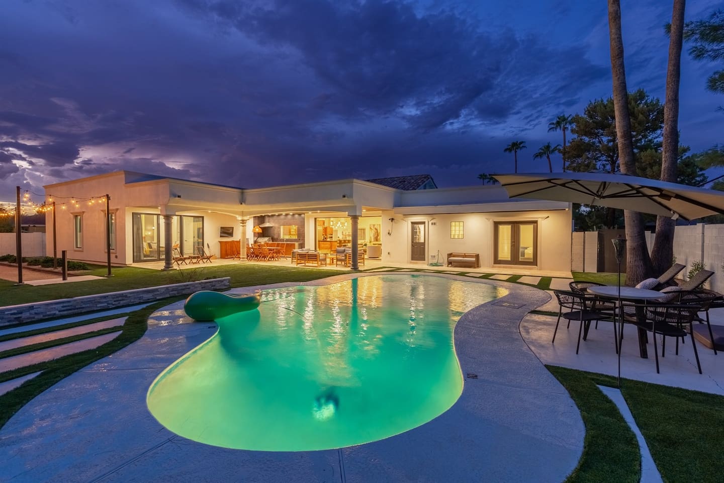 Dive into a serene poolside retreat under beautiful patio lights. Relax on comfy lounge chairs with colorful floaties for the ultimate evening escape!