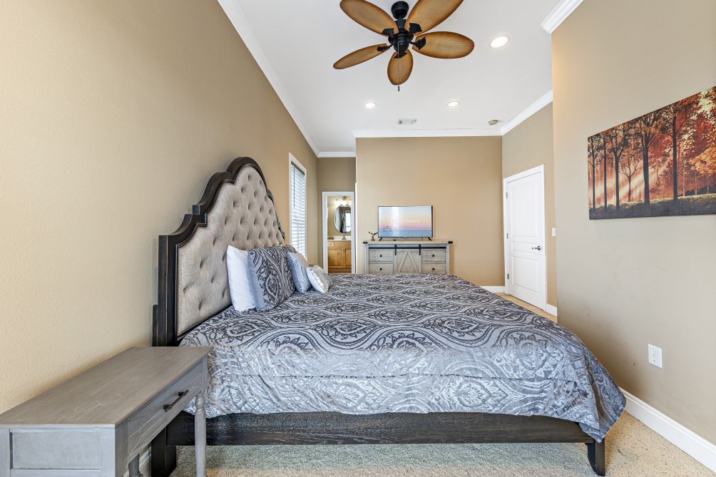 Bedroom with tufted headboard and ceiling fan