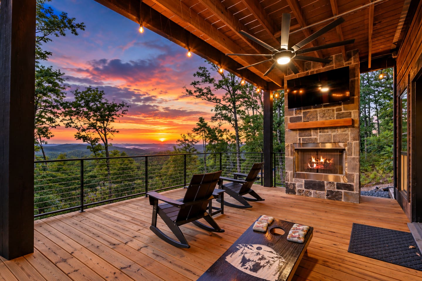Main deck with mountain views, fireplace, seating, TV and cornhole.