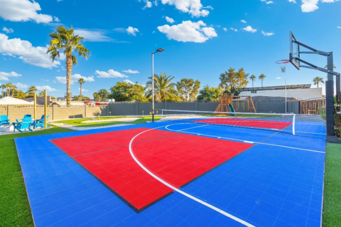 Bold color-blocked courts stretch across the yard, with the playground area visible just past the fence line.
