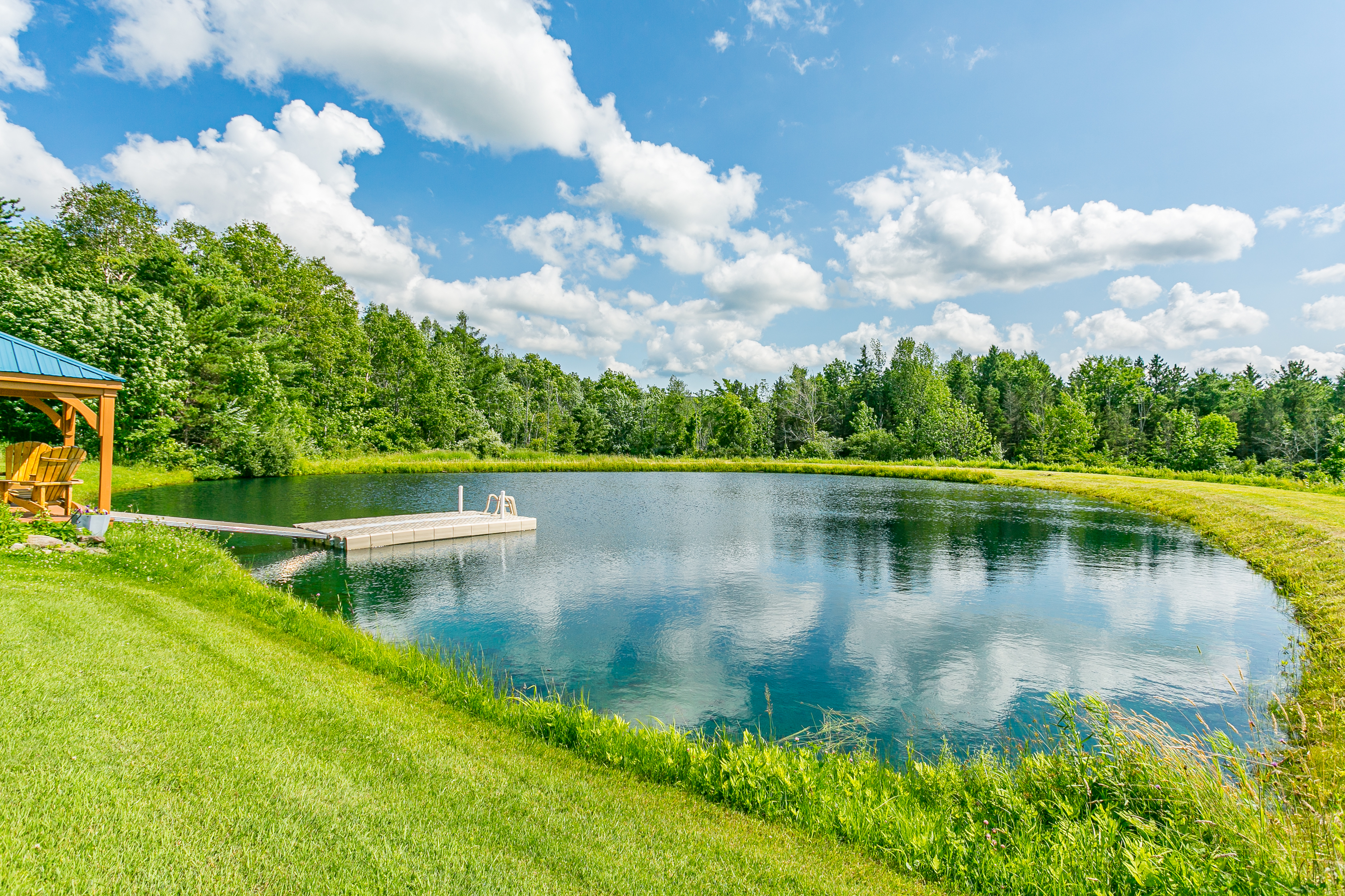 Relax Pond side under a covered pavilion with Adirondack seating and peaceful water views—an unforgettable outdoor experience.