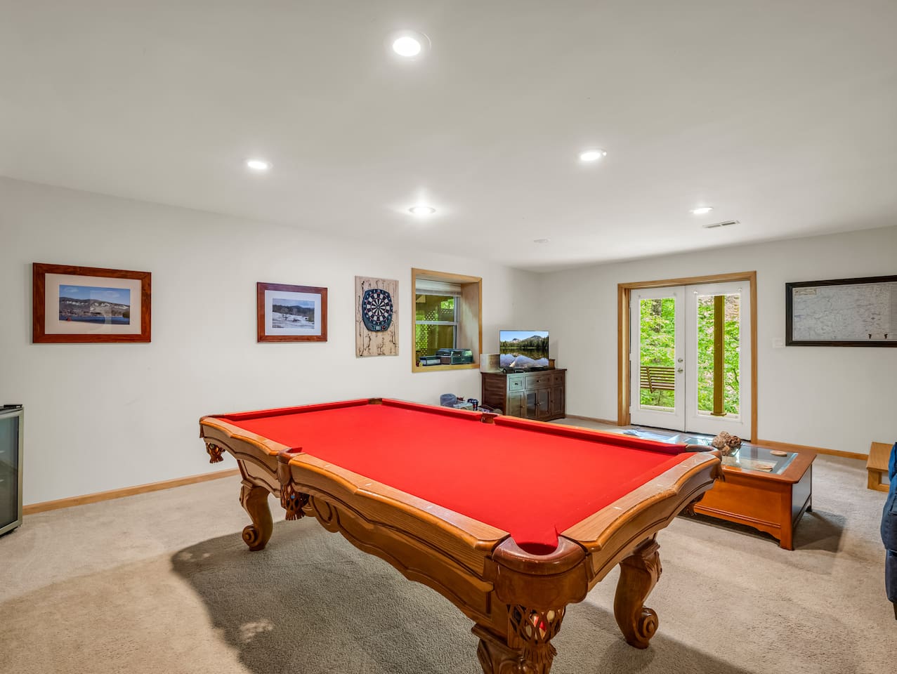 Basement with pool table, seating area, board games, and French doors leading to back patio area with swing, hot tub, and outdoor seating