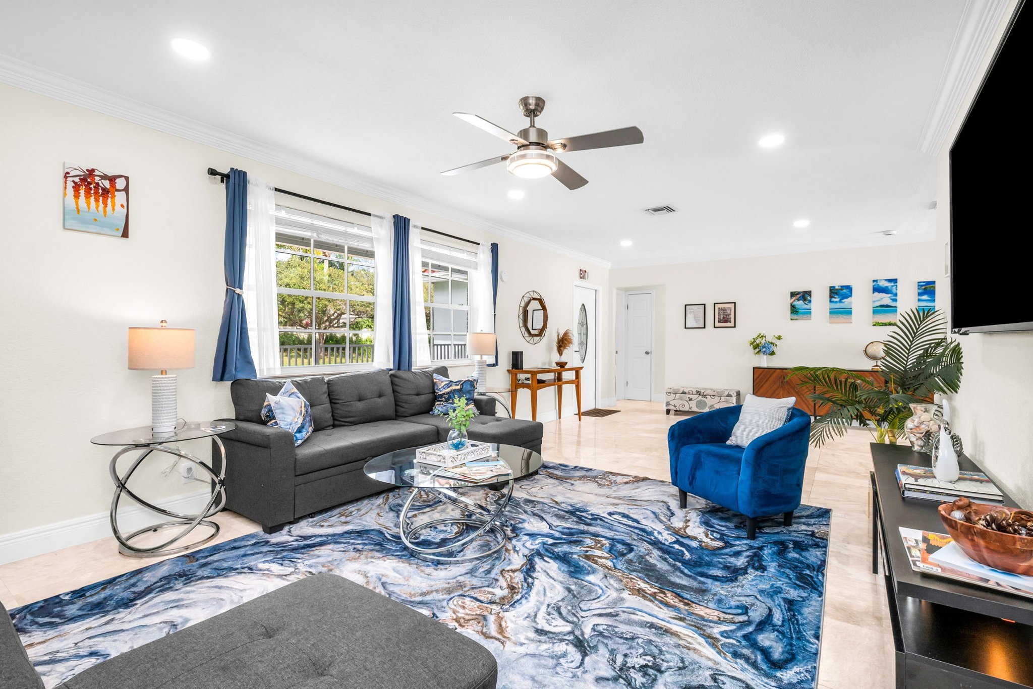 Large family-friendly living room with two queen pull-out sofas, flat-screen smart TV, and stylish coastal décor—great for groups needing extra sleeping options.