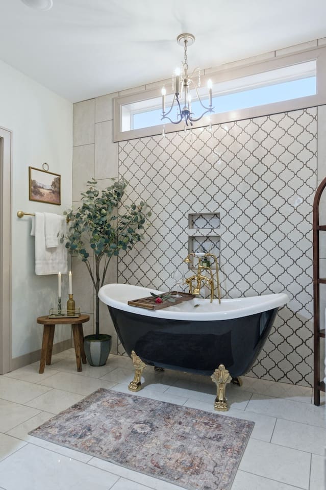 Bright and elegant bathroom featuring a statement clawfoot tub, gold fixtures, and a warm, inviting spa-like atmosphere
