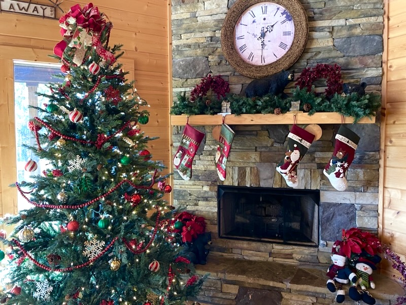 Cozy up by the crackling fireplace beside a beautifully decorated Christmas tree, where twinkling lights and stockings bring the cabin’s holiday spirit to life.