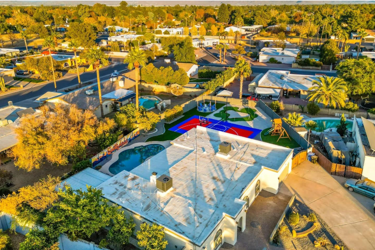 Pool, court, and putting green all visible in one frame — the kind of layout that lets everyone do their own thing at once.