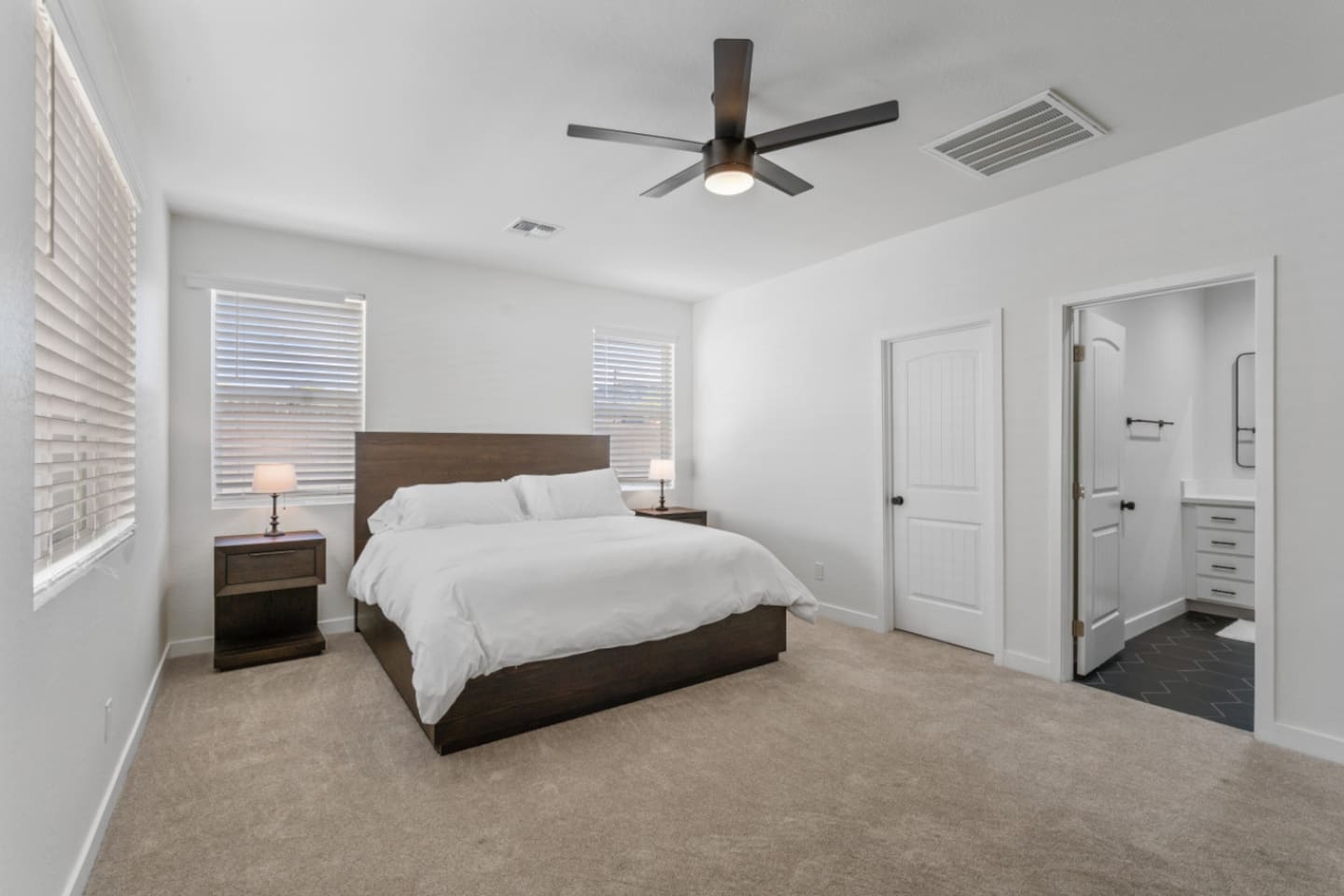 Master bedroom with ensuite bathroom access, large bed, ceiling fan, and a clean, spacious layout for a restful stay.
