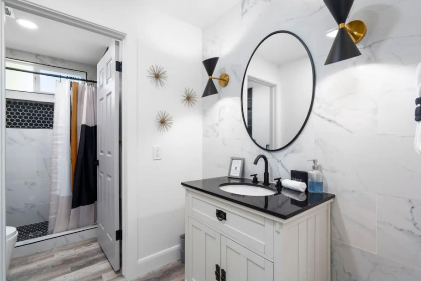 Stylish guest bathroom with marble tile, modern sconces, walk-in shower, and designer finishes.