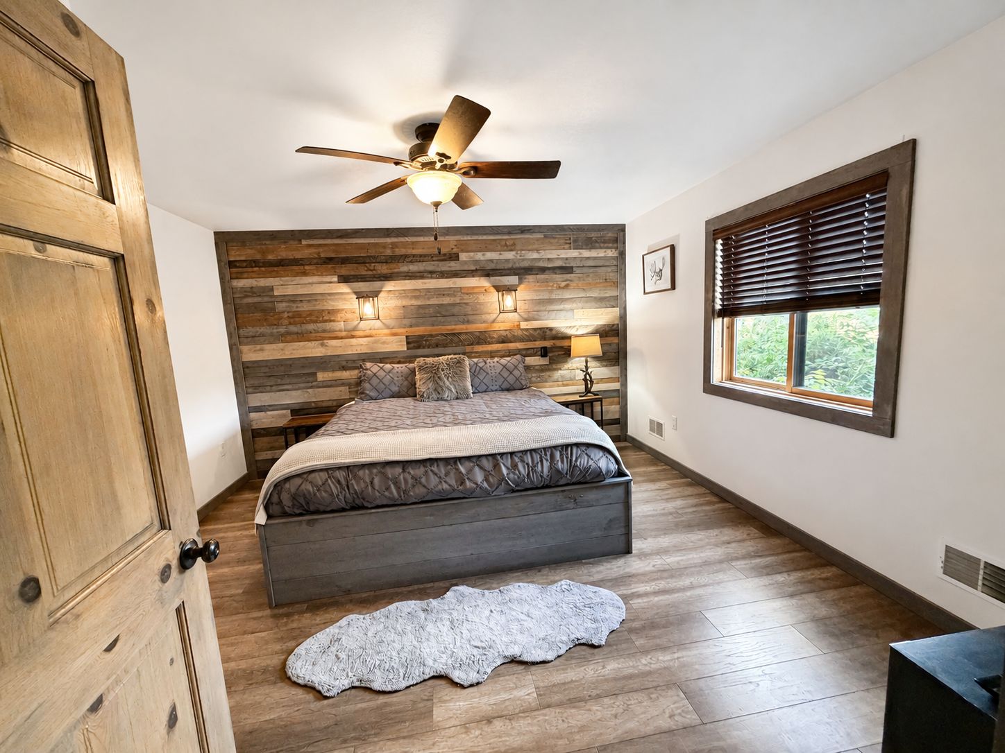 Comfortable private bedroom with warm wood accents, ceiling fan, natural light, and a relaxing Northwoods atmosphere for unwinding after a full day of Wisconsin adventures.