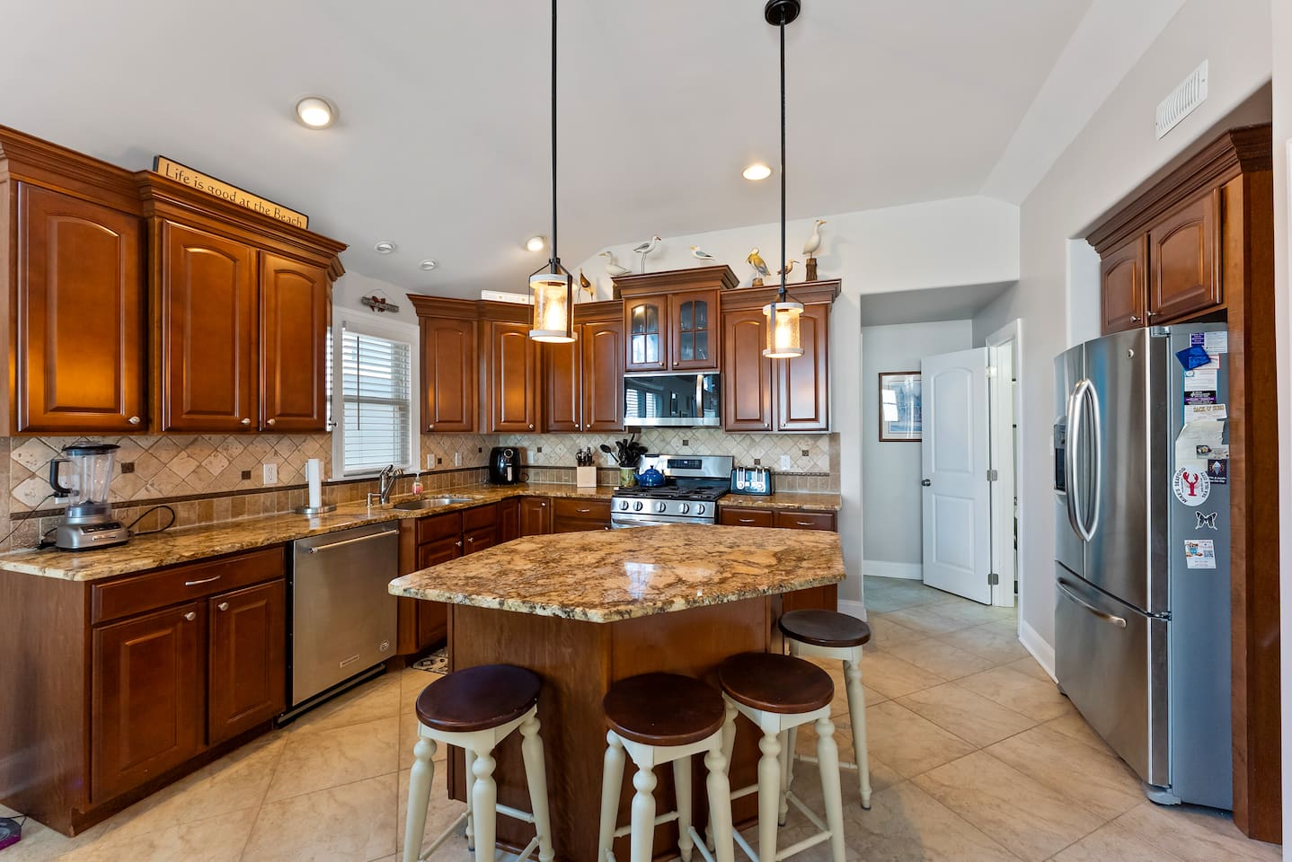 Full kitchen with stainless steel appliances, large island for additional seating, ample prep space and separate beverage refrigerator. 