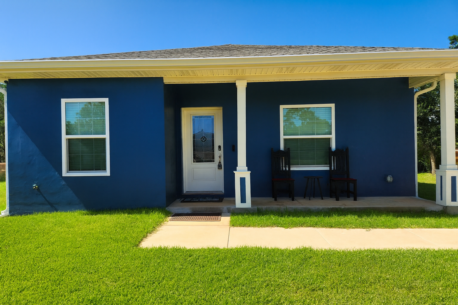 Step up to this inviting front porch, where classic columns and a bold navy exterior set the tone for a relaxing stay.