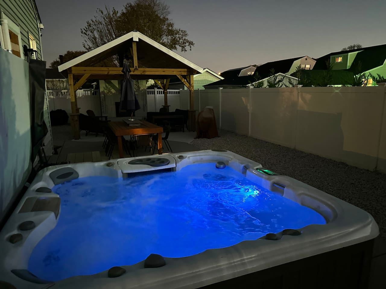 Indulge in ultimate relaxation under the stars in our glowing blue hot tub. This private backyard oasis features a spacious patio with a dining table and a covered lounge, perfect for soothing escapes during your vacation.