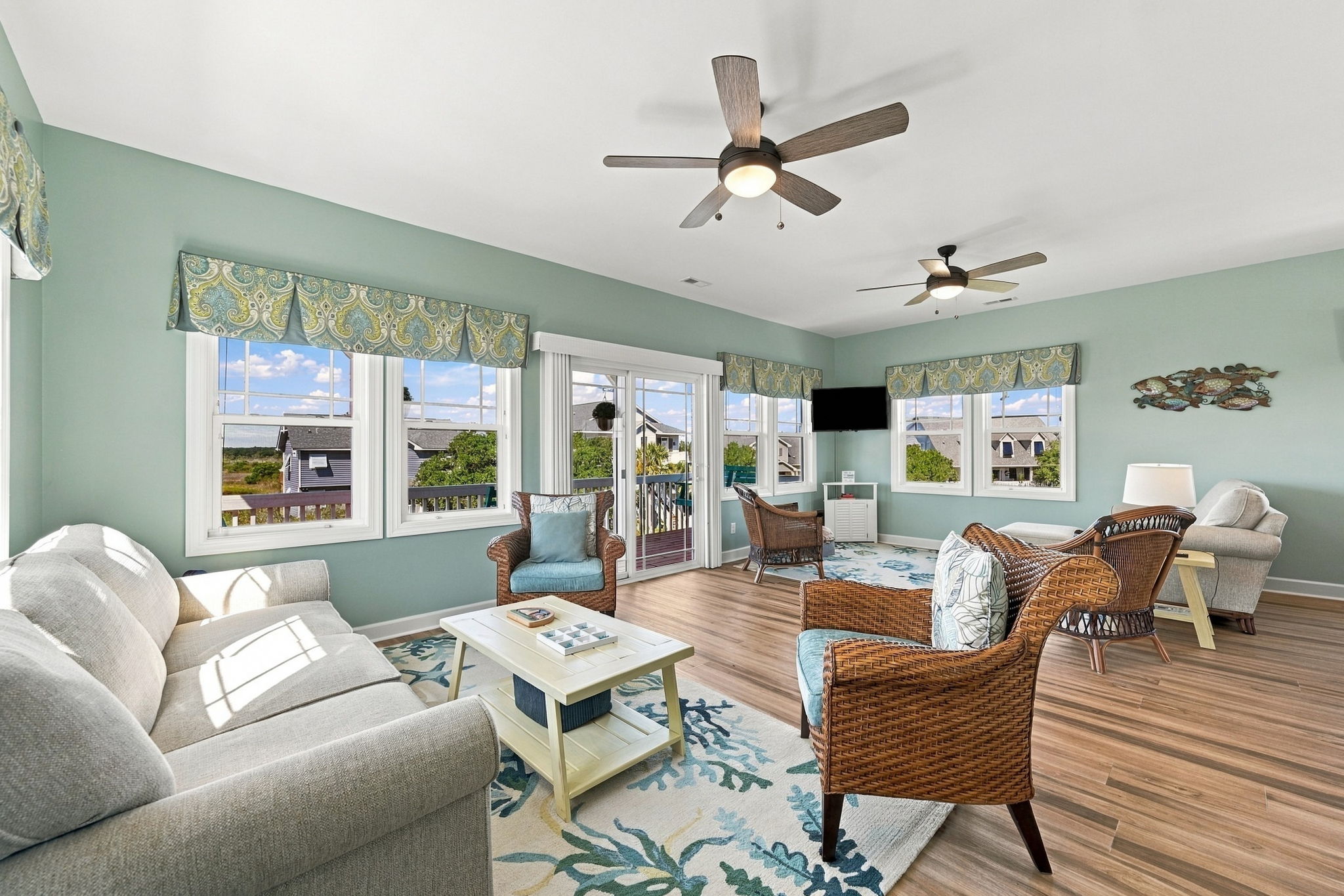Sun-filled living space with comfortable seating, coastal accents, and direct access to the outdoor deck