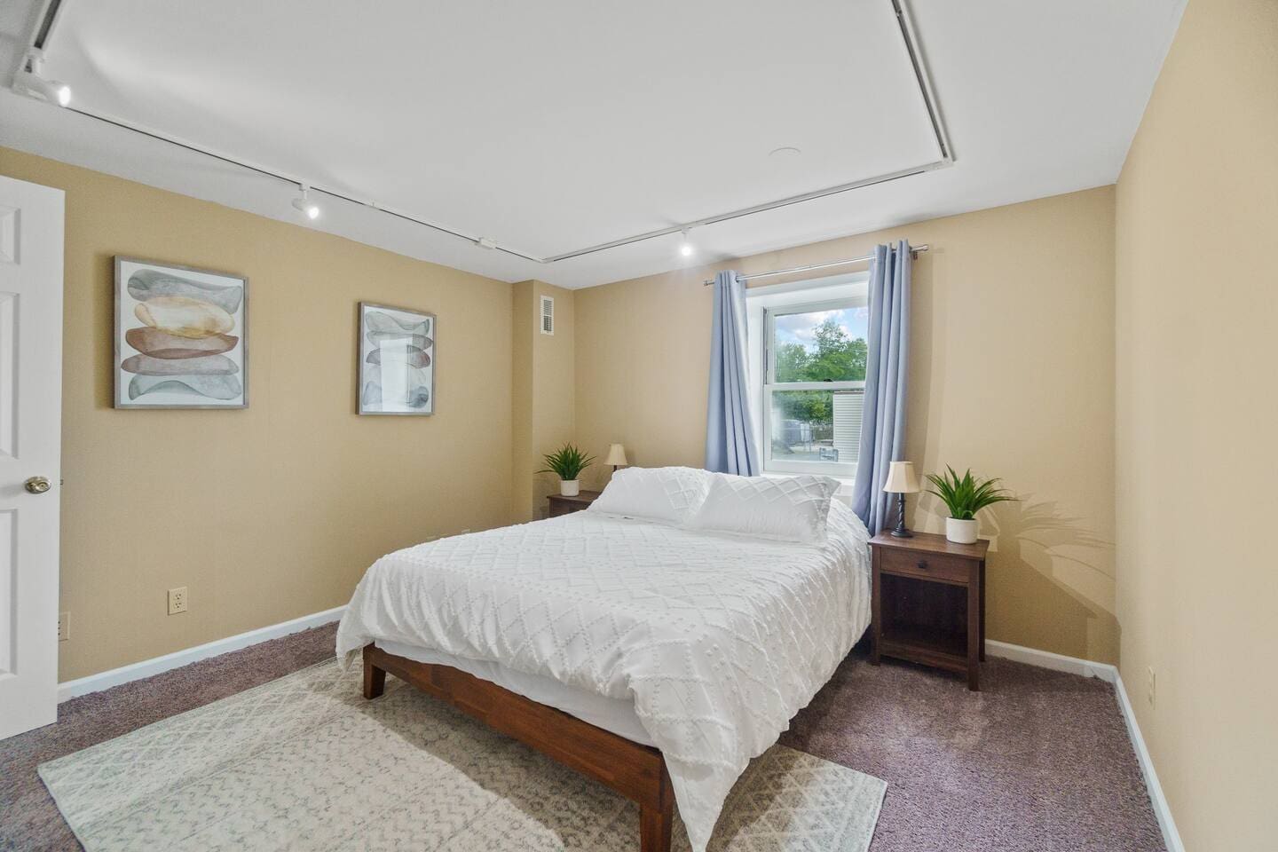 Spacious queen-sized bed with a large window, allowing natural light to fill the room and creating a bright, airy atmosphere.