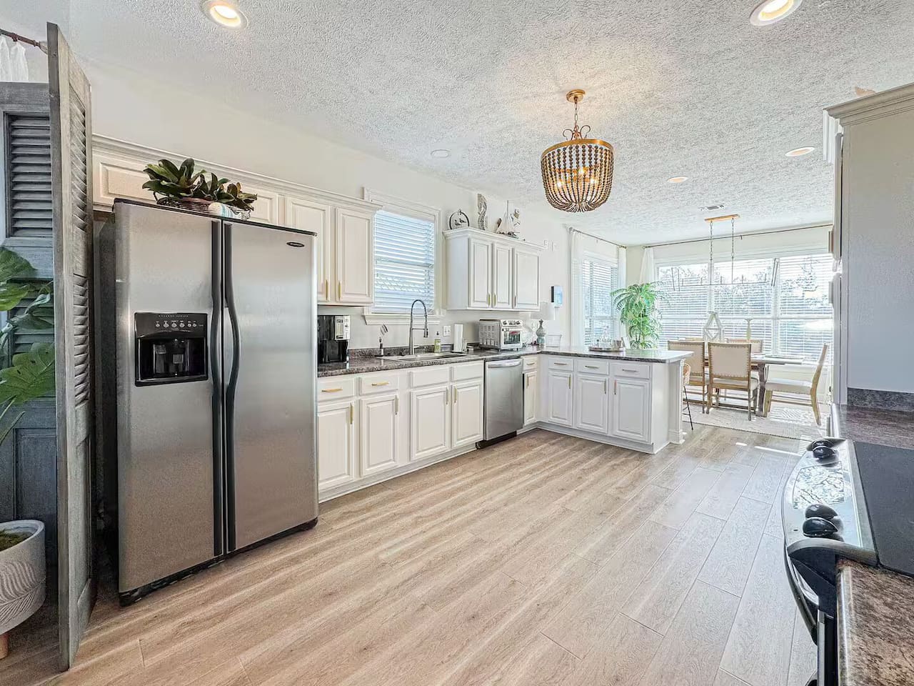 Airy kitchen with clean white finishes, wood-style flooring, and an open layout that connects effortlessly to the living space.