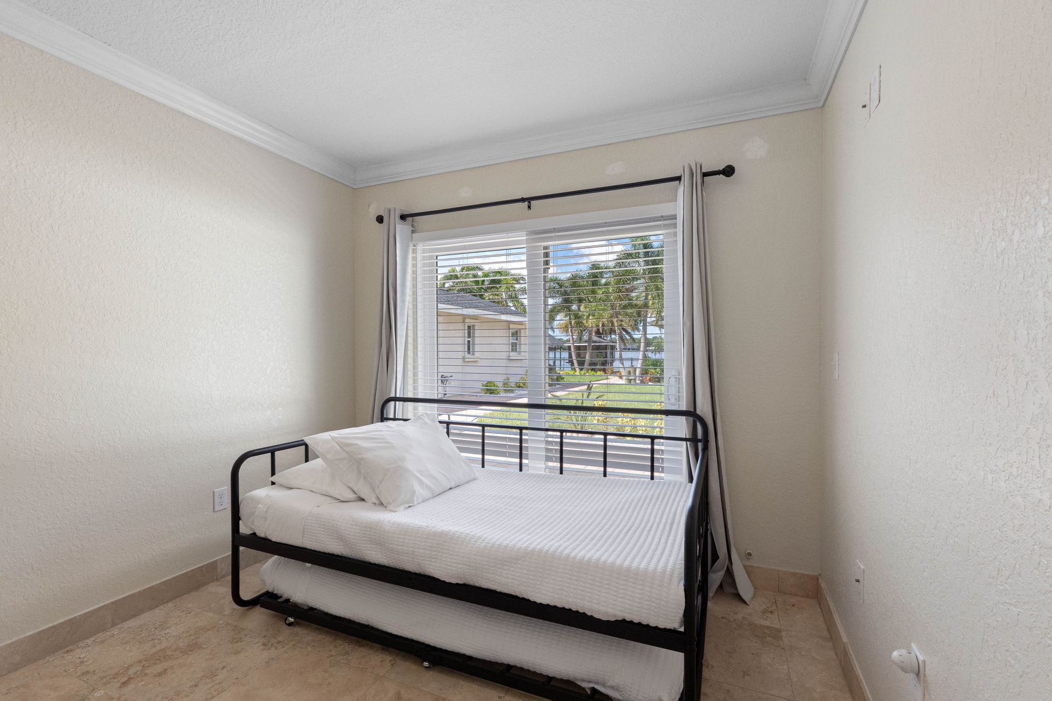 This cozy room features a daybed with trundle, perfect for flexible sleeping arrangements, and a large window with views of the yard and water beyond.