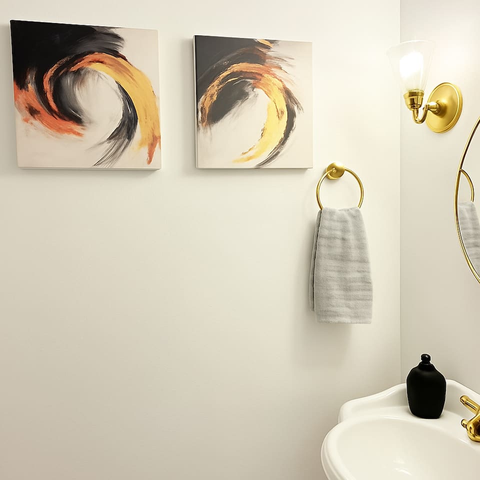 Stylish bathroom with hooks, framed art, and functional storage for towels or toiletries. 