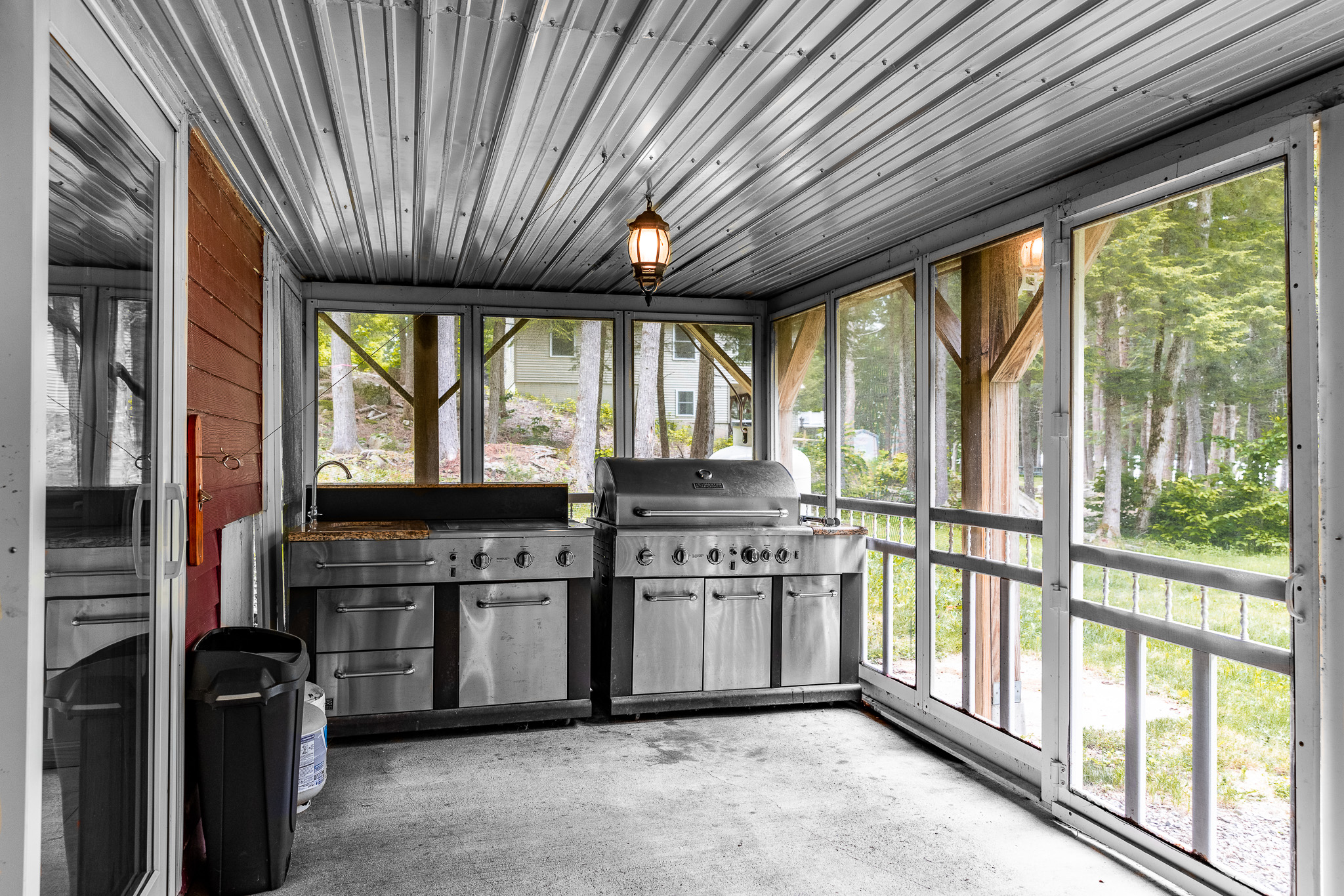 Outdoor kitchen with grill, prep area, and griddle under the covered and screened deck overlooking the lake.