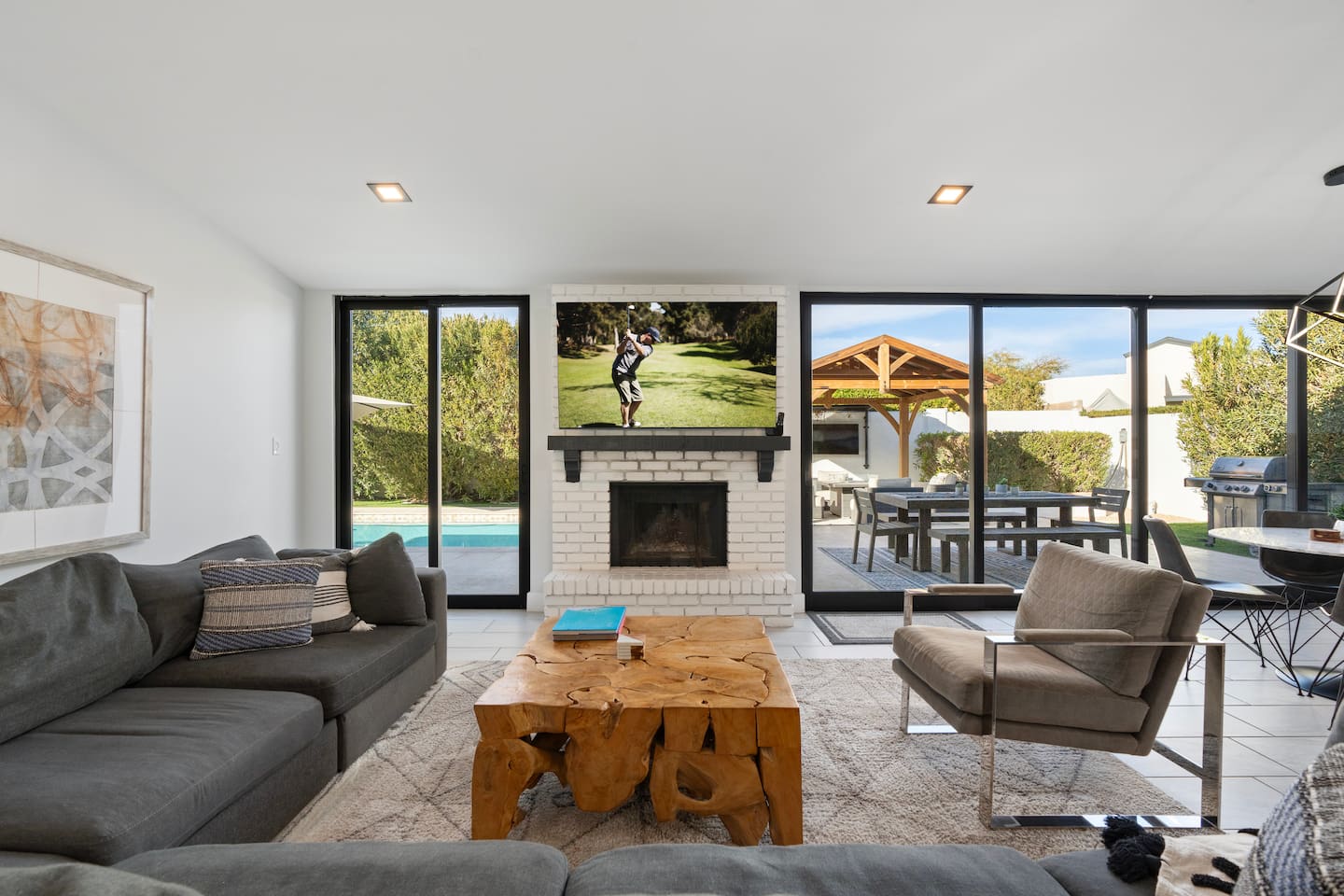Cozy living area filled with natural light from large windows, offering a beautiful view of the pool.