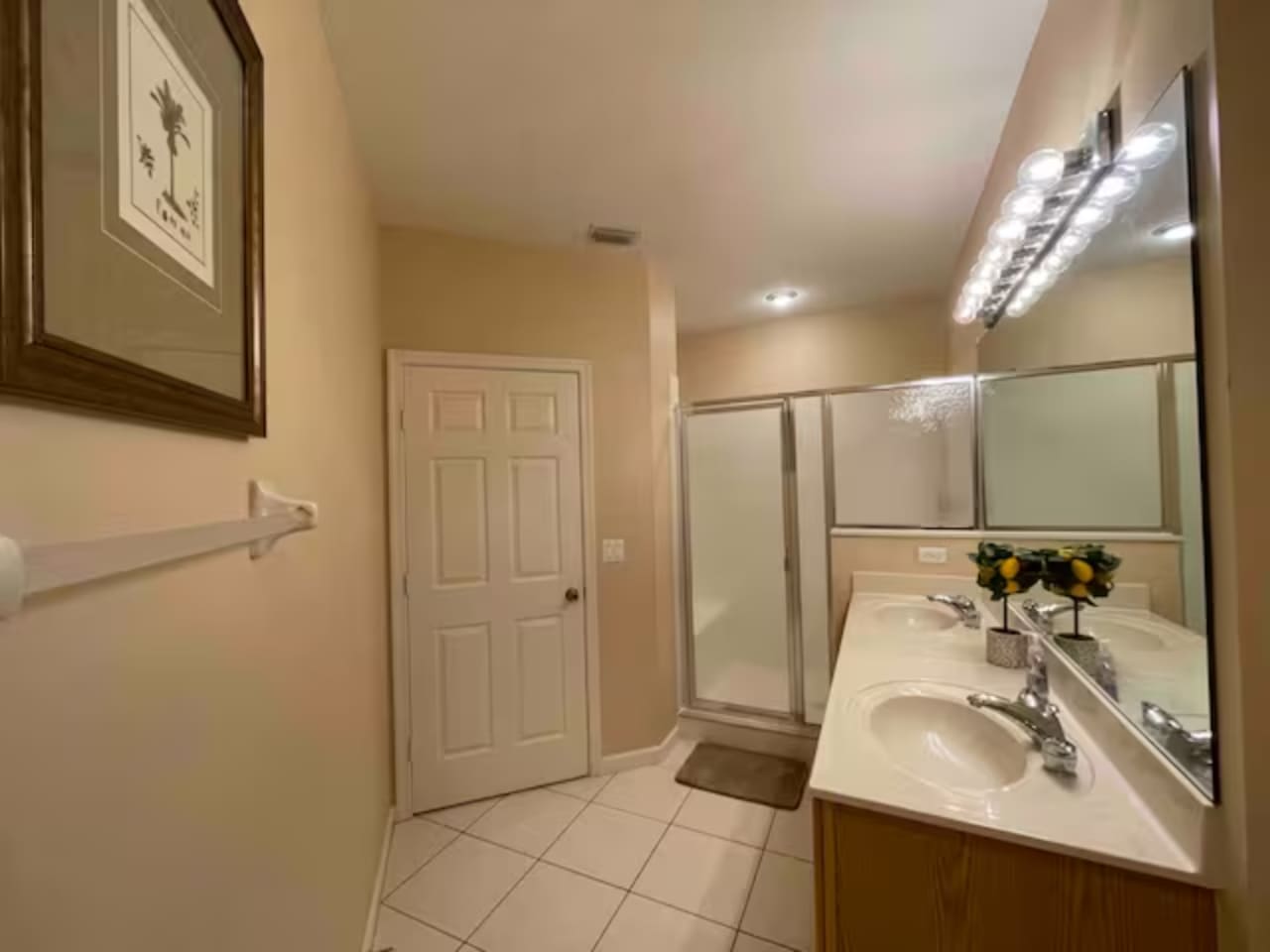 Bright bathroom with a large vanity, tile flooring, full mirror, and walk-in shower.