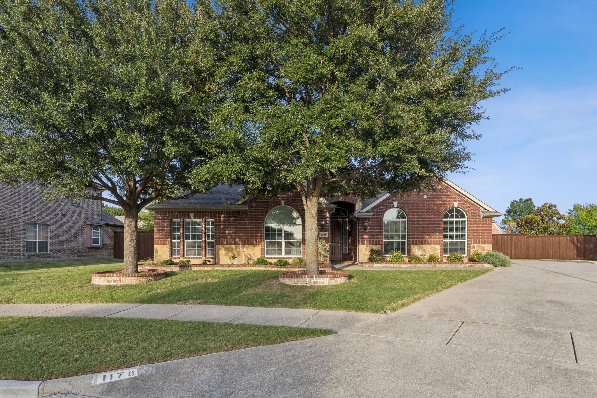 Beautifully landscaped front yard framed by mature shade trees. 