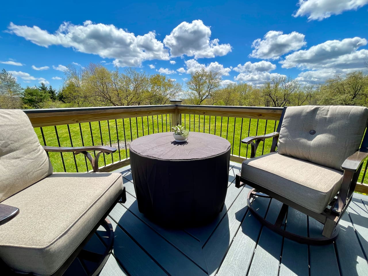 Swivel chairs around propane fire pit on deck overlooking the meadow and pond (not pictured).