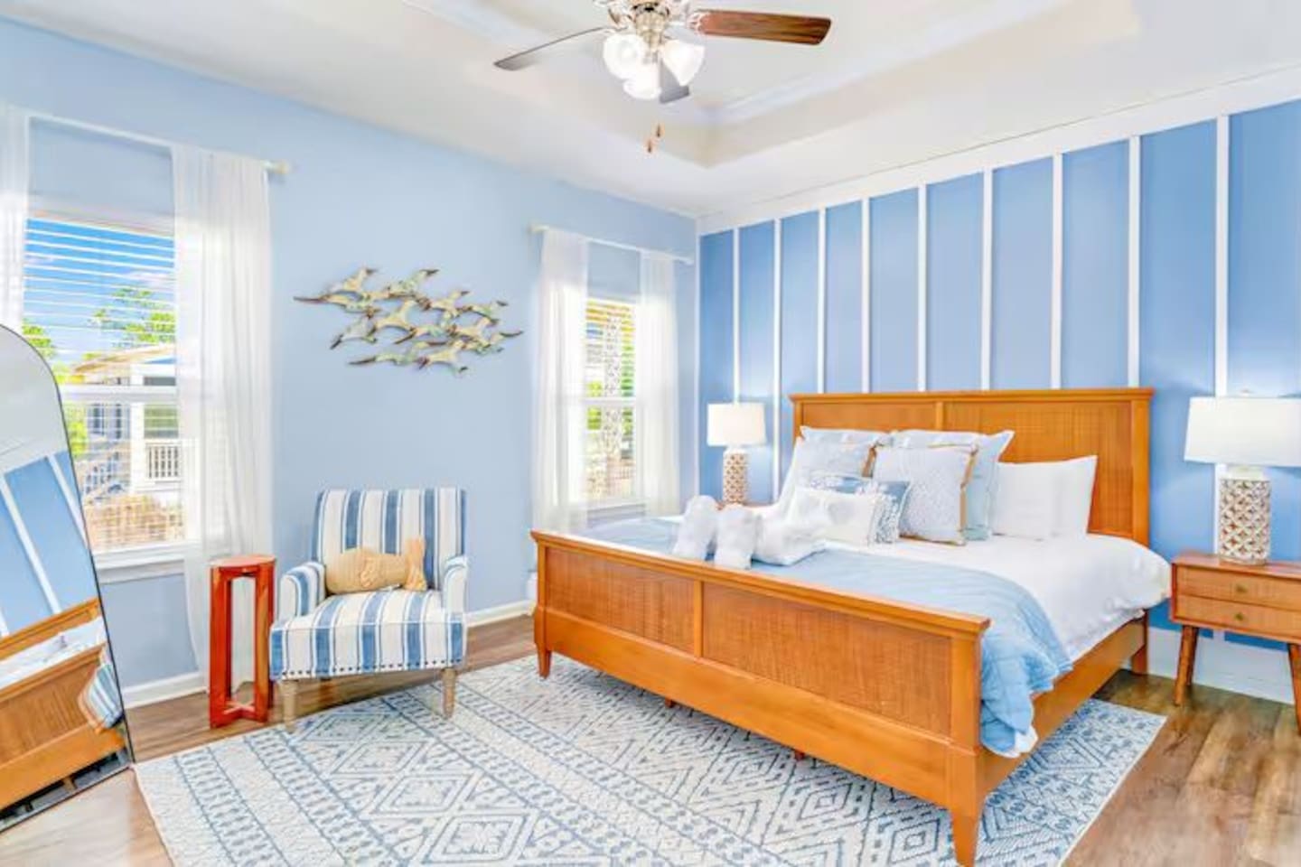 Unwind in this beautifully designed king bedroom featuring ceiling fan, bedside lamps, couch, and relaxing beach-inspired decor