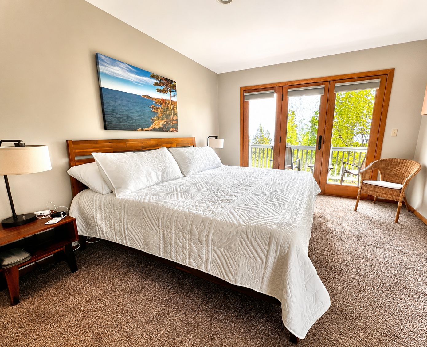 Serene primary bedroom upstairs featuring a plush king bed, large windows with breathtaking Lake Superior views, and access to a private deck. This tranquil retreat offers the perfect blend of comfort and natural beauty.