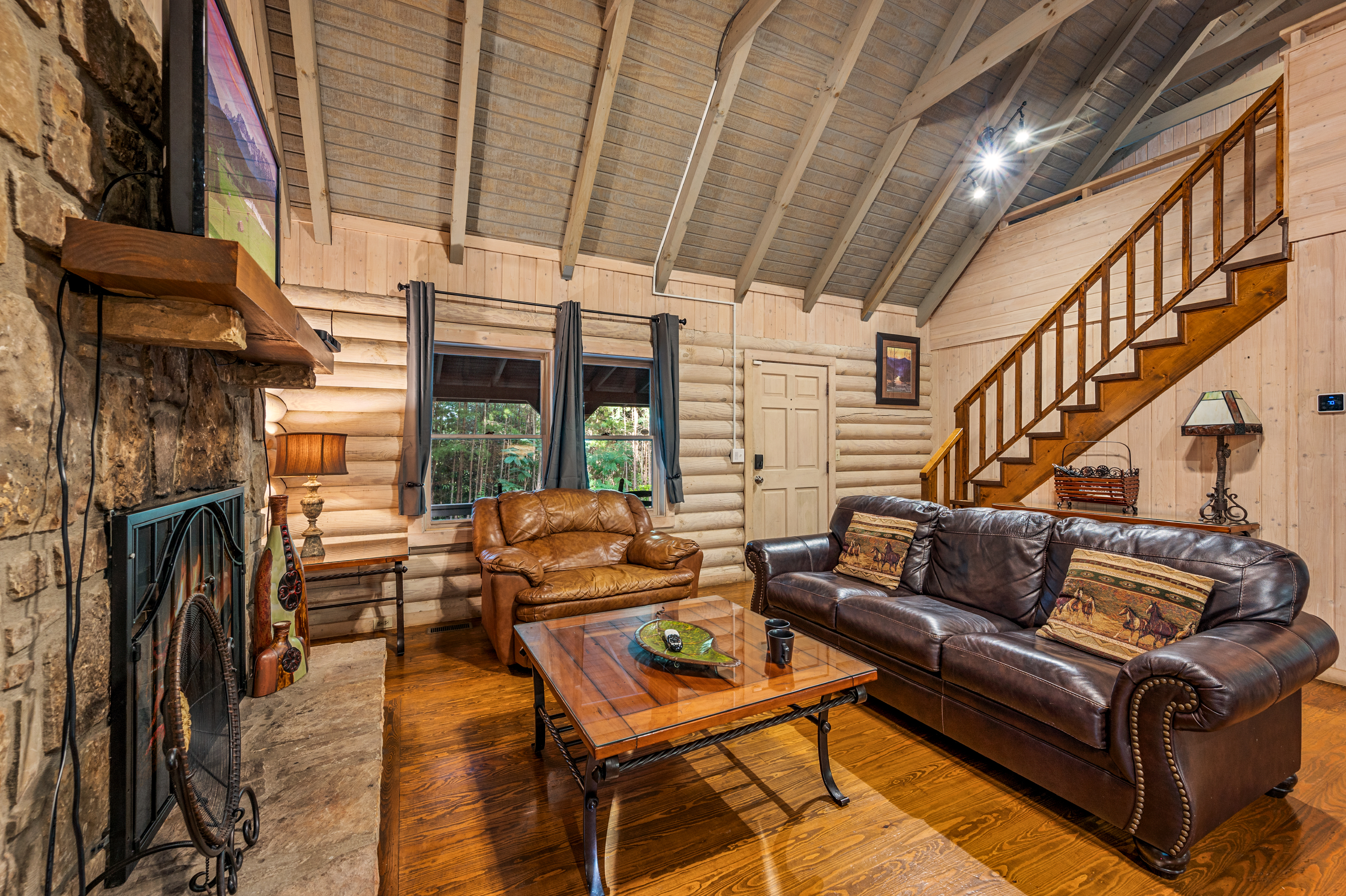 Inviting cabin living room with stone fireplace & comfortable leather seating.