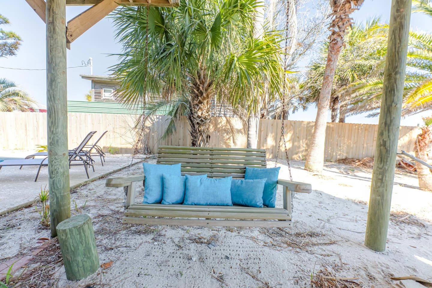 Outdoor Oasis: Relax on this charming swing surrounded by palm trees and soft sandy bliss!