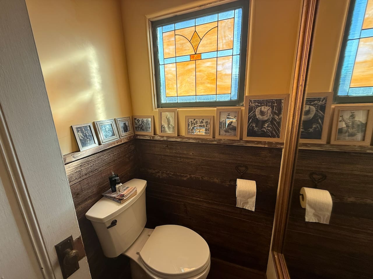 The second powder room with a matching stain glass window, ranch fencing paneling, and plaster walls. 