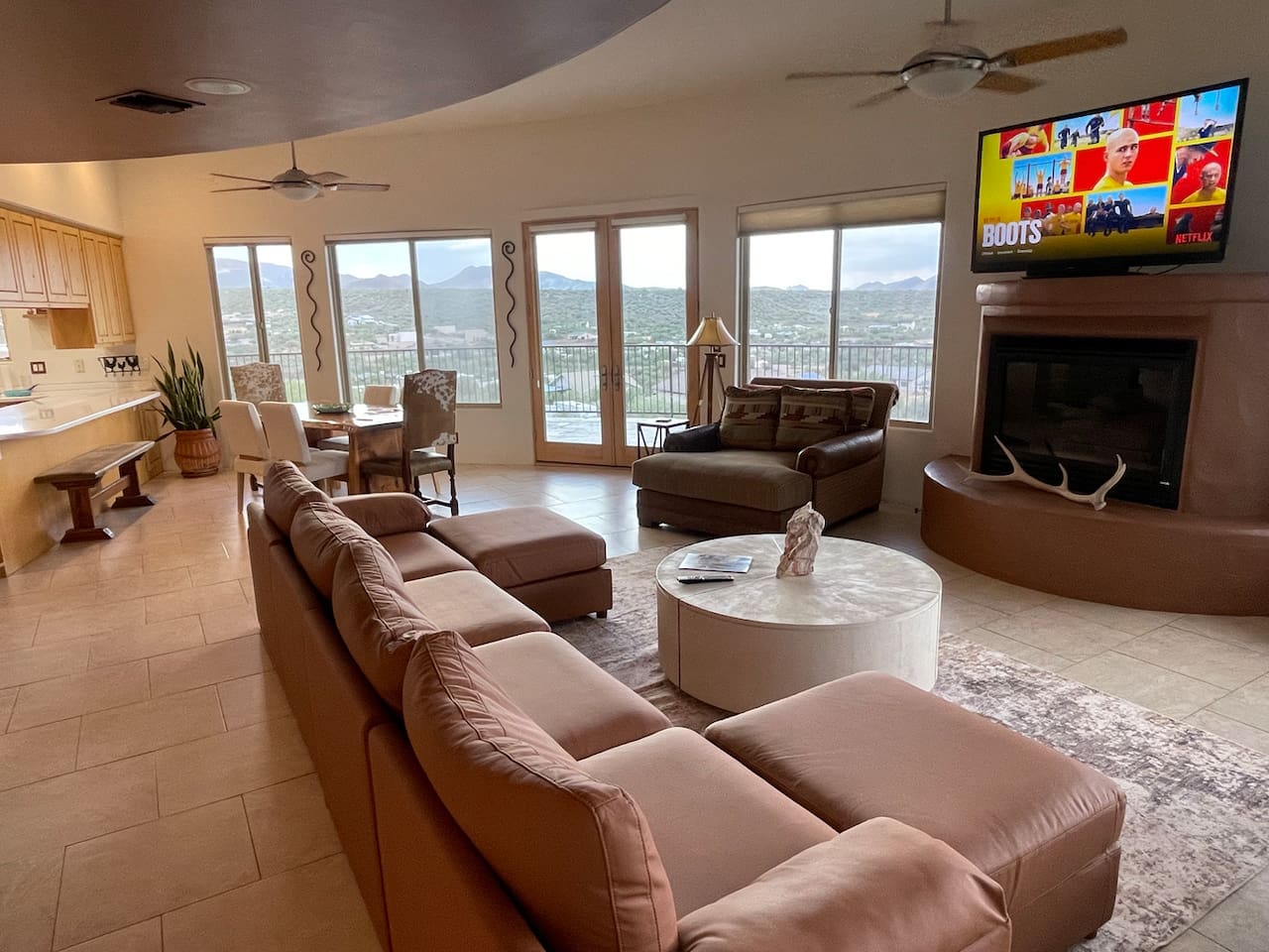 Settle into the spacious living room with comfortable seating, a fireplace, TV, and large windows that fill the space with natural light.
